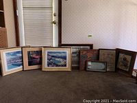 Photo showing all 8 framed wall art items arranged on carpet, includes three photographic prints and five textile pieces