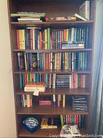 Full bookshelf with multiple shelves filled with hardcover and paperback books in varied genres.