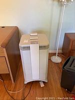 Front full view of white IQAir HealthPro Series air purifier between furniture