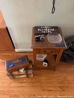 Photo of wood accent table with protective glass top, drawer, decorative trunk, music box, small plate and Panasonic Lumix camera on top
