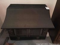 Front angled view of the Le Marquis wood burning stove showing the top ventilation and overall body with two front doors and decorative side panels.
