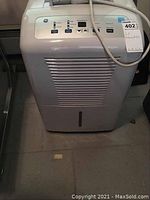 Front view of GE white dehumidifier showing vent grille and power cord