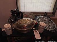 Photo showing Fire King 467 oval casserole with gold gilt grapevine lid, ceramic oil and vinegar dispensers, glass coffee pot and divided serving dish on table.