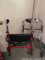 Photo showing red walker with black padded backrest and wheels