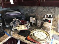 View of Black & Decker toaster oven with bakeware on top, manual slicer, toaster, Braun espresso maker, tart pans and glass.