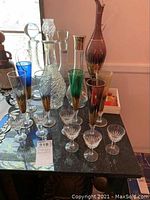 Full view of decanters and multicolored glasses on countertop showing size and variety