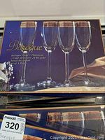 Box of Baroque Gold & Platinum fluted crystal glasses, includes four in picture with gold and platinum rim, packaging reads 'Baroque Gold & Platinum Crystal Stemware 24 kt gold band decorated set of 4 pieces'.