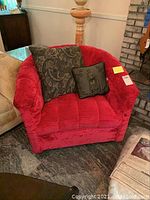 Front view of one red crushed velvet tufted armchair with two decorative pillows.