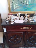 View of ceramic items on black table surface including lamps, vases, espresso set, and silver candle holders.