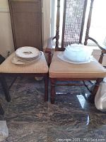 Overall view showing stacks of ceramic fish motif dishes on left chair and stacks of glass fish motif plates and platters on right chair.