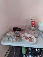 Wide view of assorted glassware, tea cups with saucers, pitchers, and bowls on table
