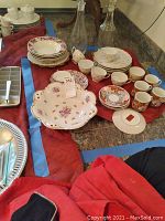 Photo showing assorted George Briard fine china including cups, saucers, various plates, and a decorative bowl, all arranged on a countertop with some glass bottles in the background.