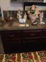 Wide view showing all porcelain figurines including dogs, larger floral centerpiece, and silver plated desk calendar