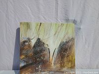 Front angled view of abstract gold and brown toned painting on stretched canvas showing texture and coloration.