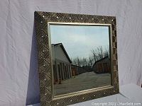 Front view of large square mirror with decorative detailed frame.