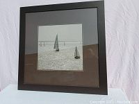 Full view of framed print showing sailboats on water with dark wood grain frame and dark grey matting.