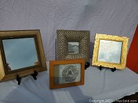 Full lot view showing two mirrors and two photo frames on black stands against a light purple background.