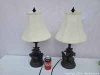 Front view of both lamps side by side showing elephant detailed bases and white lamp shades with a soda can for scale.