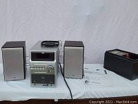 Full view of JVC stereo system with two speakers, instruction manual, and leather box with CDs.