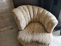 Front angle view of vintage shell back lounge chair showing fabric pattern and cushion shape.