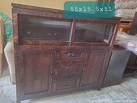 Front view of the solid wood bar/display cabinet showing sliding glass doors on the upper section, drop-down drawers in the middle, and wooden cabinets below. Dimensions displayed on top of cabinet.