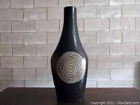 Full front view of the large black ceramic vase with white spiral dot design.