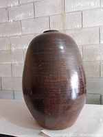 Front view of tall brown ceramic vase showing glossy and matte surface details.