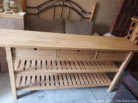 Front view of pine buffet table showing three drawers and two slatted shelves.