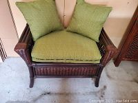 Front view of the wicker stool with green cushions showing the woven wicker details and cushion condition.