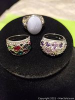 Front view of three vintage silver rings with assorted stones on black velvet display.