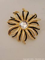 Front view of the Kenneth Jay Lane starburst brooch showing gold-tone metal, black enamel accents, and central large clear faceted stone.