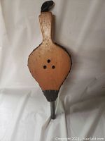 Front view of the bellows showing the wood body with three air holes and metal nozzle.