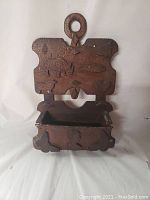 Front view of carved wooden wall-mounted box with hinged front open and decorative cutouts