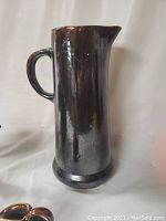 Tall dark-glazed cylindrical pitcher with handle