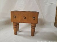 Front view of miniature wooden butcher block change tray showing overall shape and four turned legs