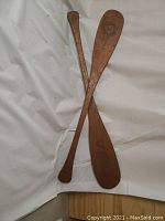 Two paddles overlapped: a narrow plain paddle and a broad pyrographed paddle