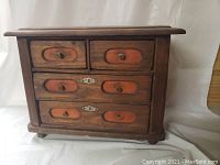 Front view of antique pine doll dresser showing six drawers with inset red panels and brass knobs