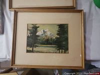 First framed mountain lake landscape painting in gold-tone frame under glass
