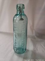 Light blue glass cod stopper bottle embossed with MYLES BOURKE BROCKVILLE lettering, standing upright on a white background to show full front detail.