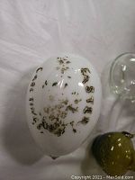 Close up of white glass Easter egg with worn gold 'EASTER GREETINGS' text.