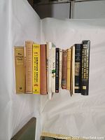 Side view of fifteen assorted books standing upright showing titles related to First Nations, Native American culture and history.