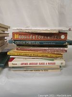 Photo showing side view stacked books with titles on their spines including Collector Knives, Chinese Porcelain, Early American Wood Carving, Antique American Clocks & Watches.