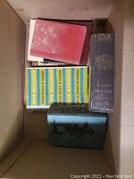 Top-down view of 7 Canadian history books in a box arranged with spines and covers partially visible.