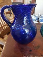 Cobalt blue pitcher with twisted pattern and spout on wooden table