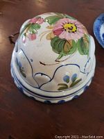Top view of ceramic jelly mold showing hand-painted pink flowers and green leaves on curved ridges