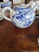 Full-size Blue Willow teapot showing traditional blue floral and landscape design on white porcelain.