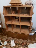 Front interior view of the wooden dollhouse showing multiple floors, interior walls, and some unfinished details.