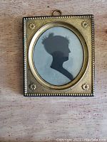 Front view of the miniature silhouette portrait showing the detailed profile and metal frame with floral accents.