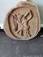 Full front view of the relief carving showing the detailed figures of David and the Angel of Death on the wood round with visible drying crack.