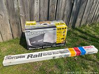 Garage door opener box and rail box on grass against wood fence showing Sears Craftsman branding and package condition